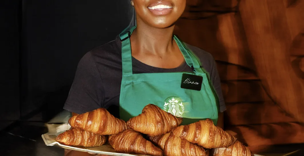 A tray of butter croissants held by a smiling Partner