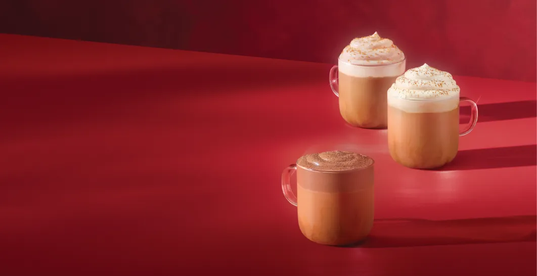 The Starbucks Holiday beverage collection arranged in a warm red environment.