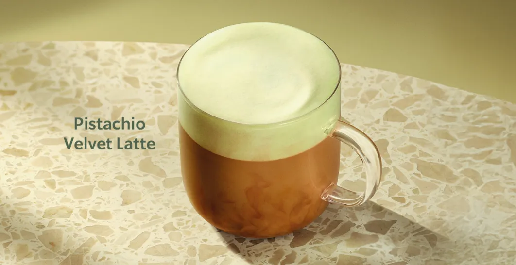 Pistachio Velvet Latte on a terrazzo table with a soft green background and delicate leaf shadows.